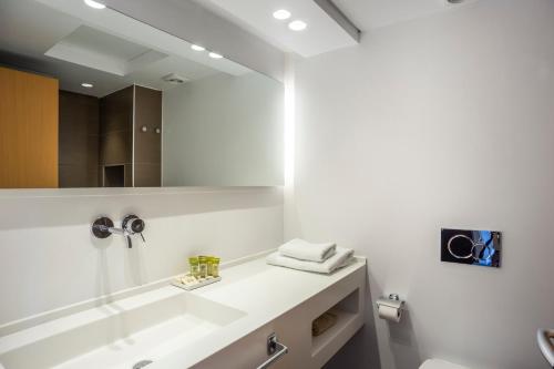 a white bathroom with a sink and a mirror at Spetses Hotel in Spetses