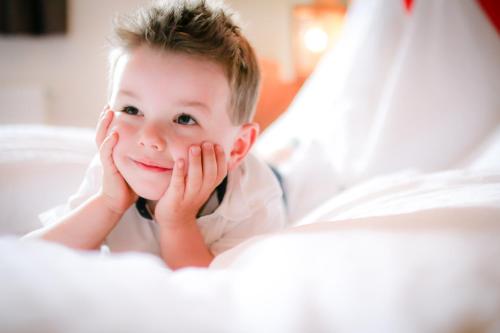 a young boy laying in a bed with his hands on his face at Gasthof Post in Rennweg
