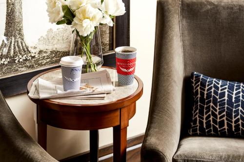 a table with two cups of coffee and a vase with flowers at The Stanford Park Hotel in Menlo Park