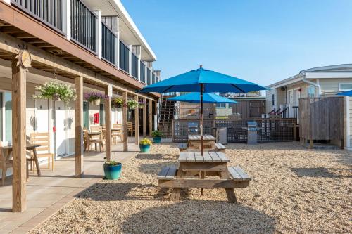 a patio with benches and an umbrella and tables at Aqualina Inn Montauk in Montauk
