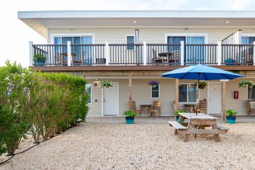 a picnic table with an umbrella in front of a house at Aqualina Inn Montauk in Montauk