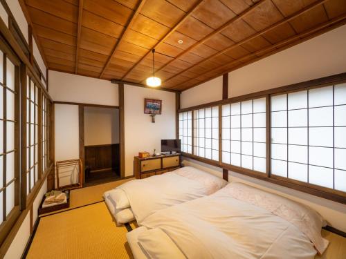 a bedroom with a bed in a room with windows at Inase Otsu Machiya Bed and Breakfast in Otsu