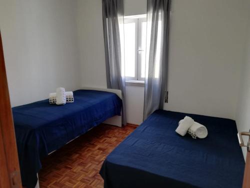 una camera con due letti con lenzuola blu e una finestra di Casa do canto a Tavira