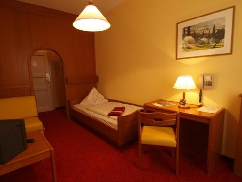 a hotel room with a bed and a desk with a lamp at Hotel Drei Hasen in Mariazell