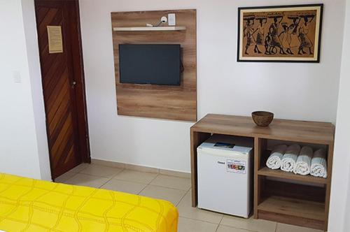 Habitación con nevera pequeña y TV. en Pousada Aconchego en Pitimbu