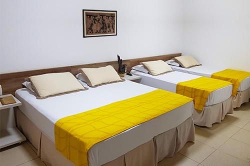 a row of three beds in a room at Pousada Aconchego in Pitimbu