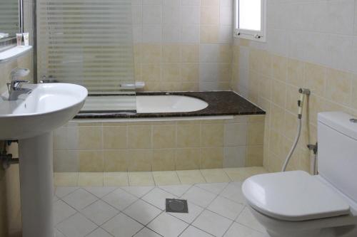 a white toilet sitting next to a sink in a bathroom at Clifton International Hotel in Fujairah