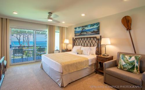 a bedroom with a bed and a balcony with the ocean at Nāpili Surf Beach Resort by Castle in Lahaina