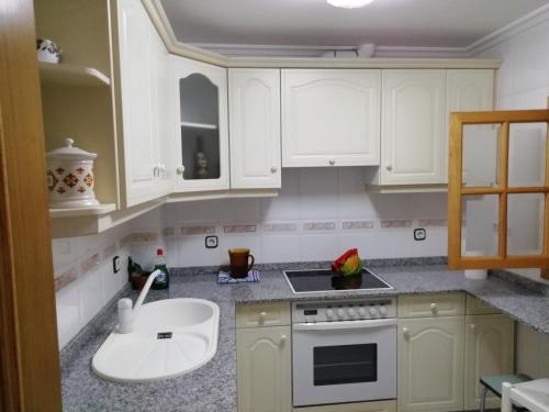 a kitchen with white cabinets and a sink at Duplex Álvaro cunqueiro, 1.3C1 in Foz