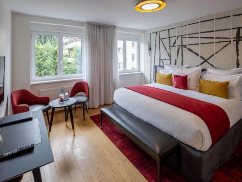 um quarto de hotel com uma cama grande com almofadas vermelhas e amarelas em Hôtel Garrigae Villa La Florangerie - Piscine extérieure em Estrasburgo