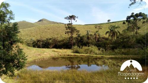 a pond in a field with mountains in the background at Hospedagem Colinas in Aiuruoca