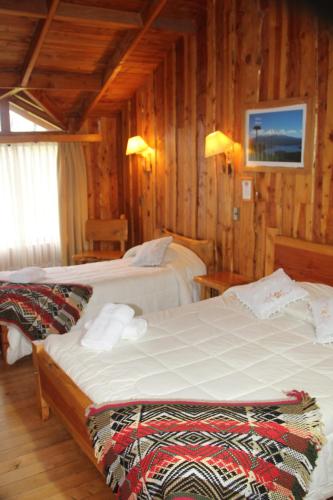 a bedroom with two beds and a tv on the wall at Hosteria-Cabañas Rucapillan in Choshuenco