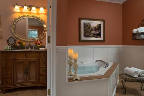 a bathroom with a tub and a sink and a mirror at 1825 Inn Bed and Breakfast in Palmyra