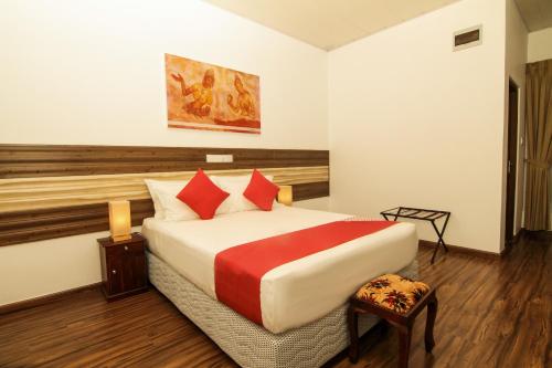 a bedroom with a large bed with red pillows at Clove Transit Hotel in Kotugoda