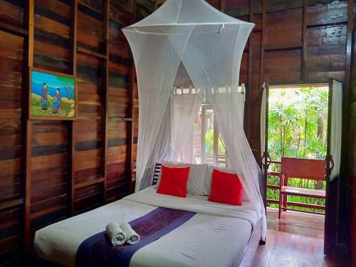 - une chambre avec un lit et une moustiquaire dans l'établissement Namkhong Guesthouse and Resort, à Chiang Khong