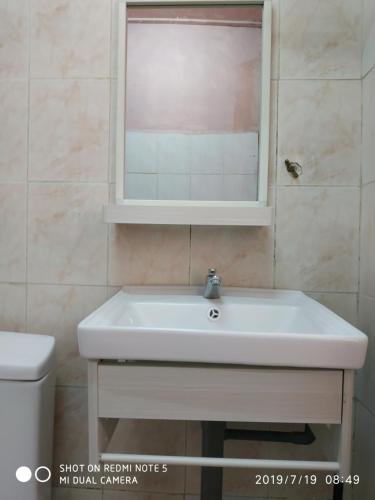 a bathroom sink with a mirror and a toilet at Nora Damin Homestay Kampong Jalan Kebun in Kampong Lombong