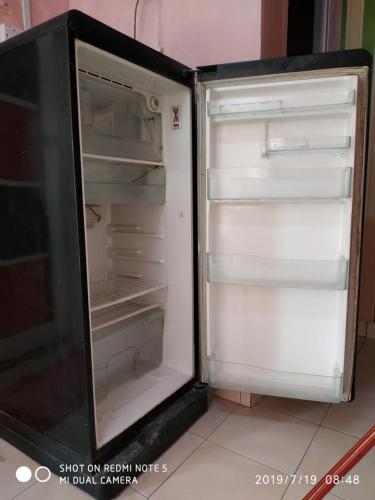 an empty refrigerator with its door open in a kitchen at Nora Damin Homestay Kampong Jalan Kebun in Kampong Lombong
