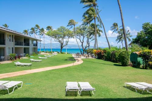 a row of chaise lounges on the lawn at a resort at Nāpili Surf Beach Resort by Castle in Lahaina