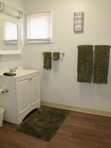 a bathroom with a sink and green towels on the wall at Little Ted's Cottages in Marblehead