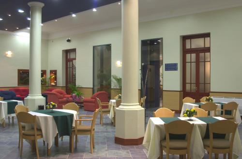 a dining room with tables and chairs and columns at Hotel Plaza Rafaela in Rafaela