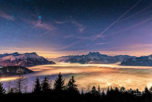 a view of a foggy valley in the mountains at night at Hôtel Le Grand Chalet in Leysin