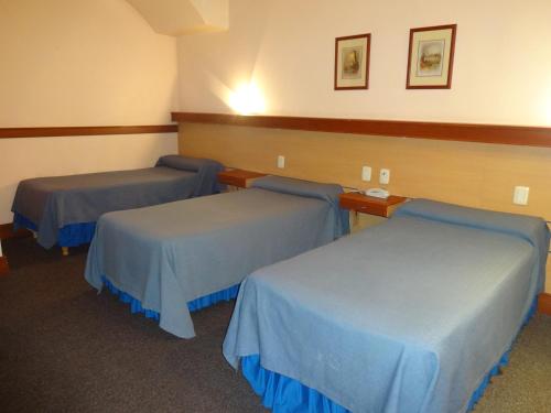 three beds in a room with blue sheets at Hotel Plaza Rafaela in Rafaela