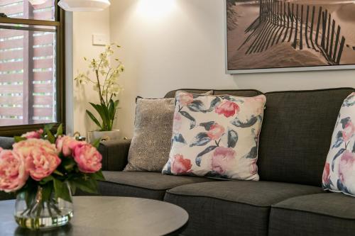 Una sala de estar con un sofá y una mesa con flores. en Calinda Sol 2 @ Clarkes Beach, en Byron Bay