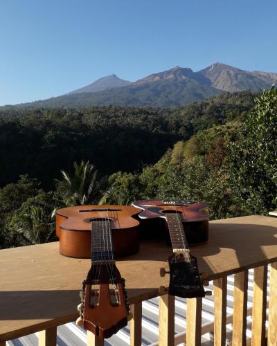 two guitars sitting on a deck with mountains in the background at Rinjani Houseboon in Senaru