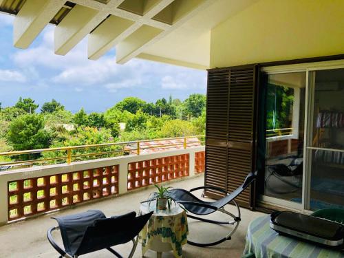 a balcony with chairs and a table and a view at Tom and Rimi's in Kumejima