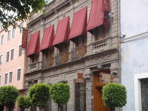 a building with red awnings on the side of it at Hotel Puebla de Anta&ntilde;o in Puebla
