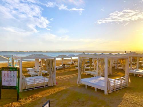 a row of white tables and umbrellas on a beach at Luxury Villa with pool in Hurghada in Hurghada