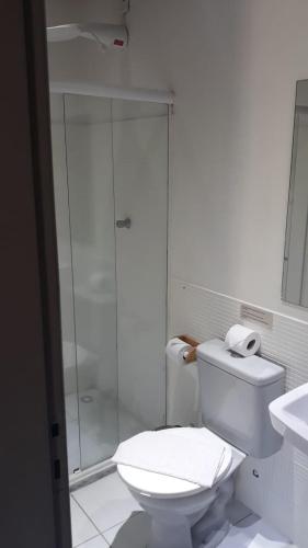 a white bathroom with a shower and a toilet at Pousada Bar Café Algas Marinhas in Praia do Forte
