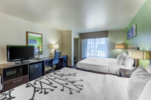 a hotel room with a bed and a flat screen tv at Sleep Inn & Suites Hewitt - South Waco in Hewitt