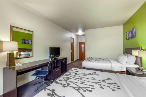 a hotel room with a bed and a desk with a computer at Sleep Inn & Suites Hewitt - South Waco in Hewitt