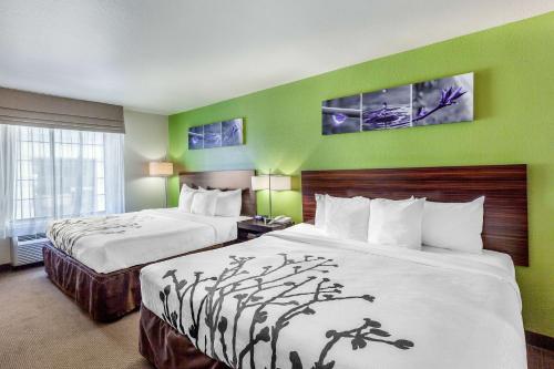 2 Betten in einem Hotelzimmer mit grünen Wänden in der Unterkunft Sleep Inn & Suites Hewitt - South Waco in Hewitt