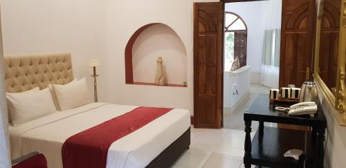 a bedroom with a bed and a desk with a phone at Ella Planters Bungalow in Ella