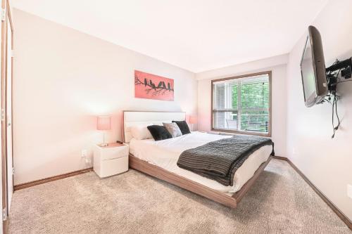 a white bedroom with a bed and a tv at The Best ski-in/ski-out at The Aspens in Whistler