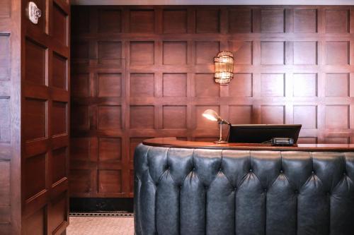 a bar with a leather seat in front of a wall at Dossier in Portland