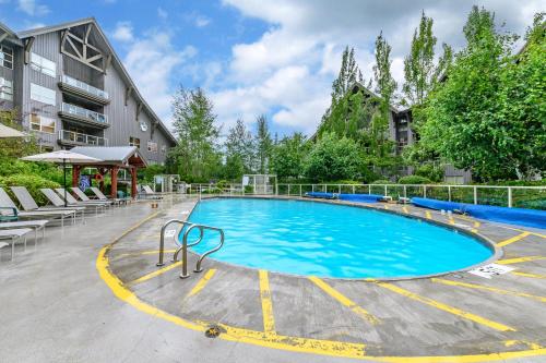 a large swimming pool with chairs and a building at The Best Top Floor Ski-in/Ski-out at the Aspens in Whistler