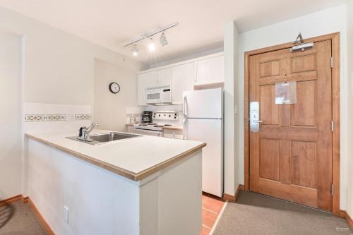 a white kitchen with a sink and a refrigerator at The Best Top Floor Ski-in/Ski-out at the Aspens in Whistler