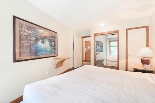 a bedroom with a white bed and a painting on the wall at The Best Top Floor Ski-in/Ski-out at the Aspens in Whistler