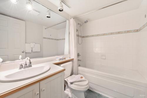 a white bathroom with a sink and a toilet at The Best Top Floor Ski-in/Ski-out at the Aspens in Whistler
