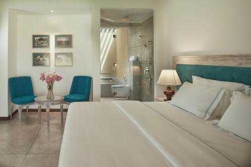 a bedroom with a large white bed and blue chairs at The Villas, Wadduwa in Wadduwa