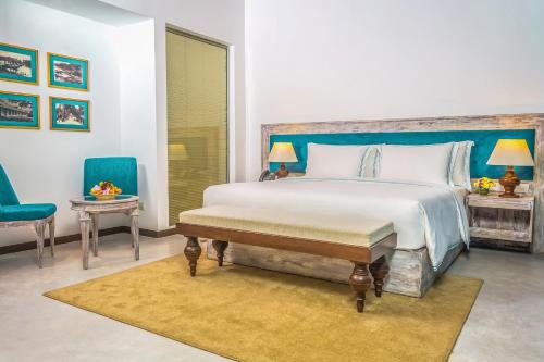 a bedroom with a large bed and two blue chairs at The Villas, Wadduwa in Wadduwa