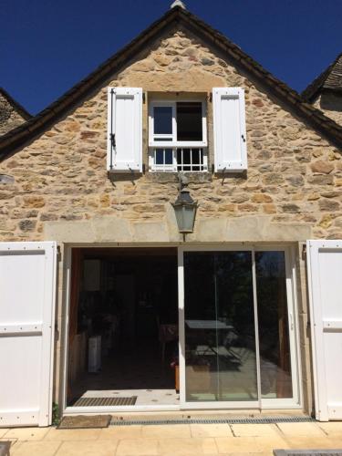 Castelnau-de-MandaillesにあるLa Source Gilhodesの白いドアと窓のある石造りの家