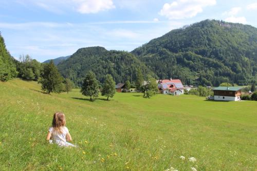 kobieta siedząca na polu trawy w obiekcie Ferienhof Kirchau w mieście Göstling an der Ybbs