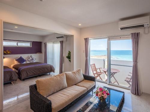 a bedroom with a couch and a bed and a view of the ocean at Yonabaru Hotel SUNRIZE OCEAN in Yonabaru