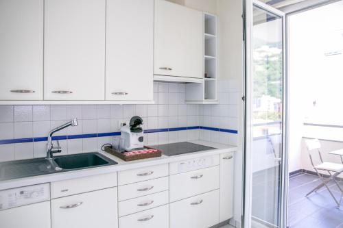 una cucina con armadi bianchi e lavandino di Schöne Ferienwohnung mit Panoramablick a Locarno