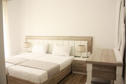 een witte slaapkamer met een groot bed en een bureau bij Alexandra´s Apartments in Sarandë