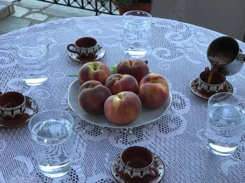 a plate of apples on a table with water glasses at Aegean House in Agios Dimitrios